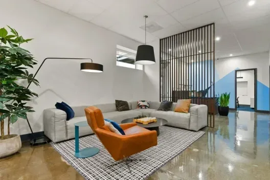 Modern common area lounge with sectional sofa and orange leather chair at the Portland facility