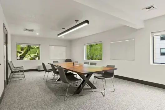 Conference room with wooden table, gray chairs, and whiteboard at the Portland facility
