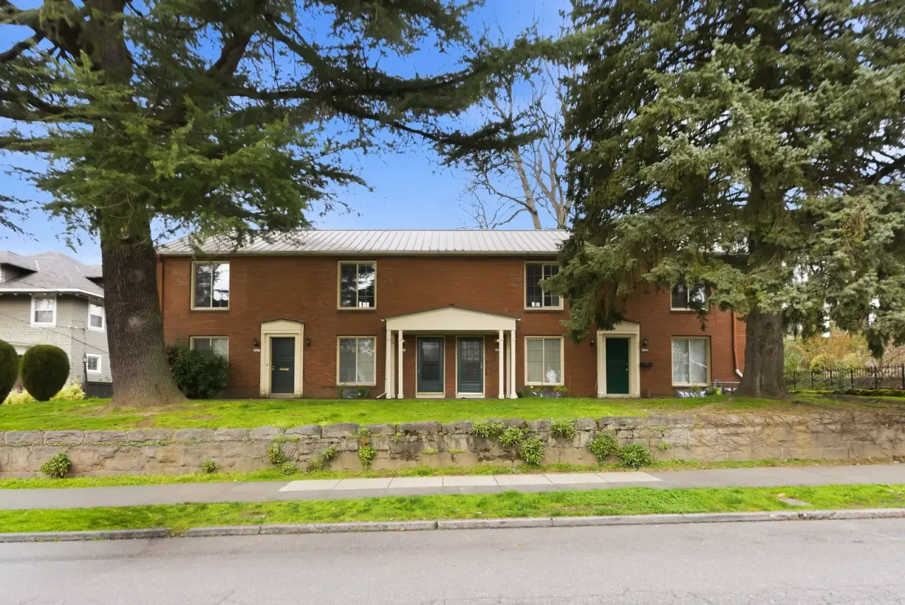 Red brick Portland sober living home with a columned portico and evergreen trees