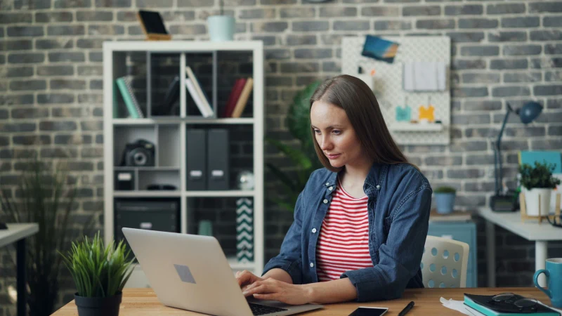 Person using a laptop at a home table during a virtual intensive outpatient session