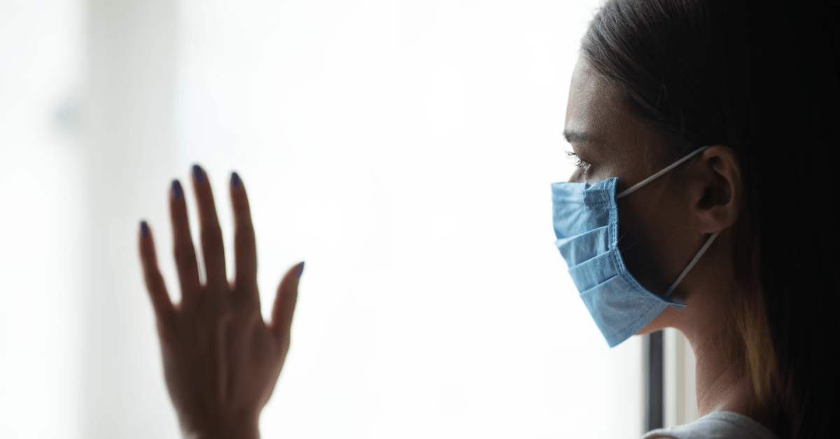 Woman in medical mask at window