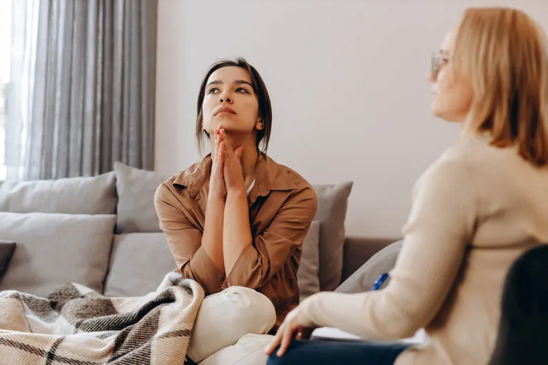 person sitting on couch with hands on neck during somatic experiencing therapy