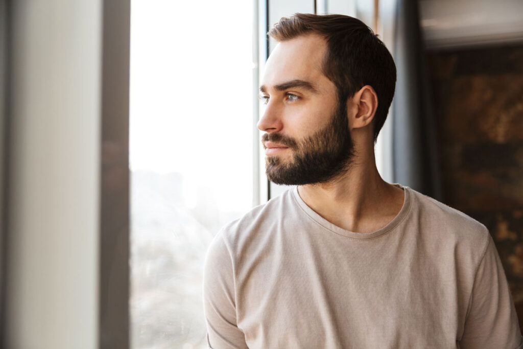 person pensively looking out window while contemplating the cocaine withdrawal timeline